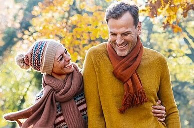 Ein lachendes Pärchen läuft durch einen herbstlichen Wald